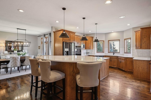 kitchen with stainless steel appliances, backsplash, brown cabinetry, and a center island