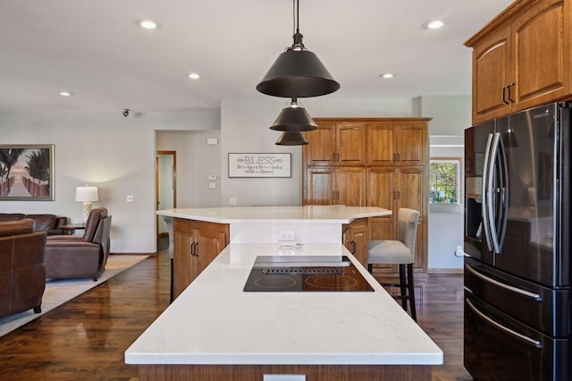 kitchen featuring a spacious island, black electric cooktop, refrigerator with ice dispenser, and dark wood finished floors