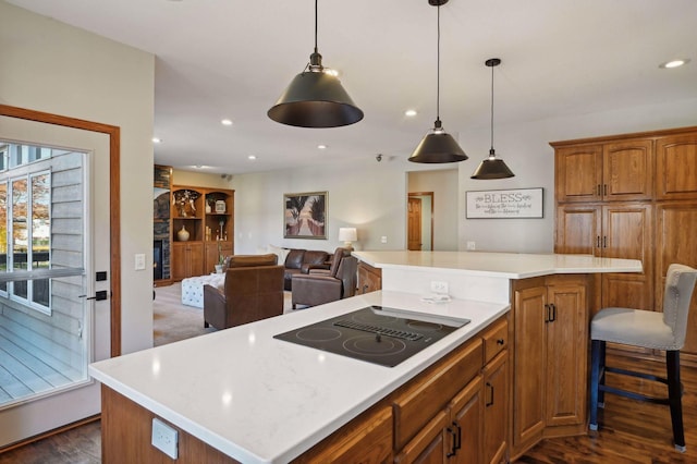 kitchen featuring light countertops, a kitchen island, brown cabinets, black electric cooktop, and open floor plan