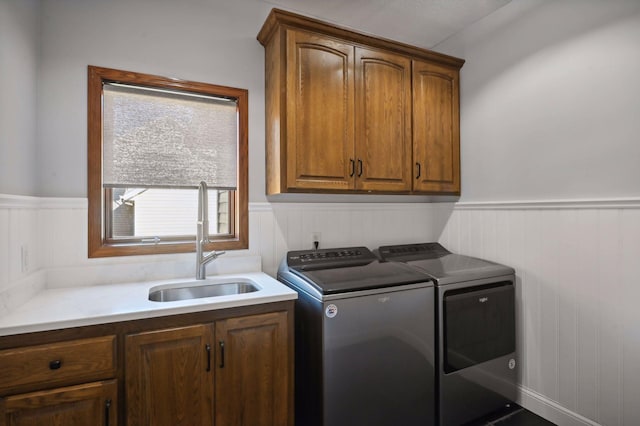 laundry room with a sink, a wainscoted wall, separate washer and dryer, and cabinet space