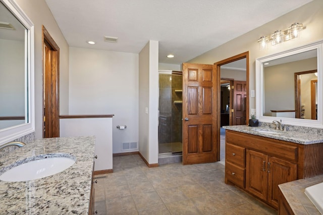 bathroom featuring two vanities, visible vents, a stall shower, and a sink