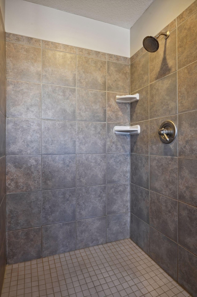 bathroom with a tile shower and a textured ceiling