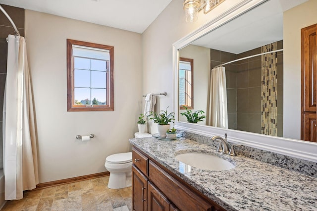 bathroom with stone finish floor, toilet, tiled shower, and baseboards