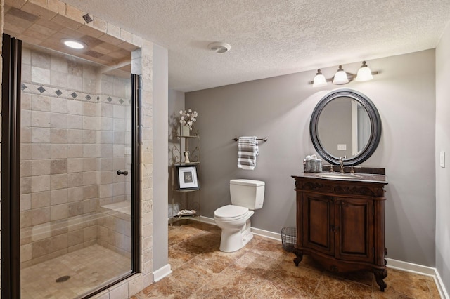 bathroom with toilet, vanity, baseboards, a stall shower, and a textured ceiling