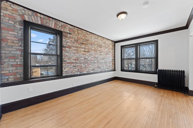 2218 Nicollet Ave Unit 22, Minneapolis, MN 55404 - unfurnished room featuring baseboards, ornamental molding, radiator, brick wall, and wood-type flooring