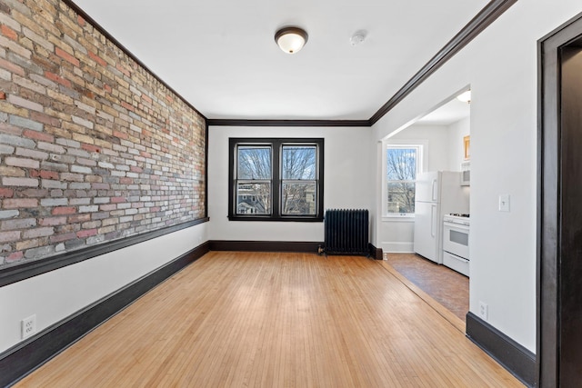 2218 Nicollet Ave Unit 22, Minneapolis, MN 55404 - unfurnished room featuring crown molding, wood finished floors, radiator, brick wall, and baseboards
