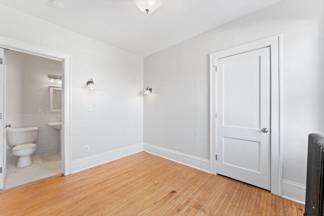 2218 Nicollet Ave Unit 22, Minneapolis, MN 55404 - unfurnished bedroom with hardwood / wood-style floors, baseboards, ensuite bath, and tile walls