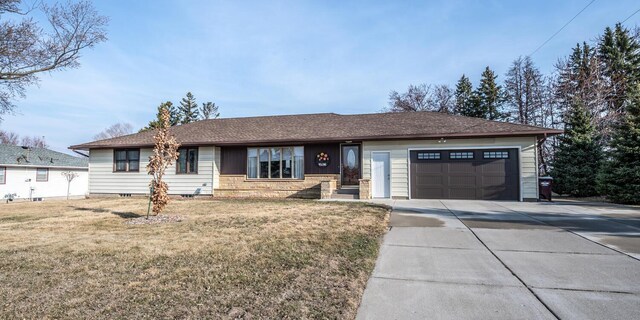 ranch-style home featuring an attached garage, a front lawn, and concrete driveway