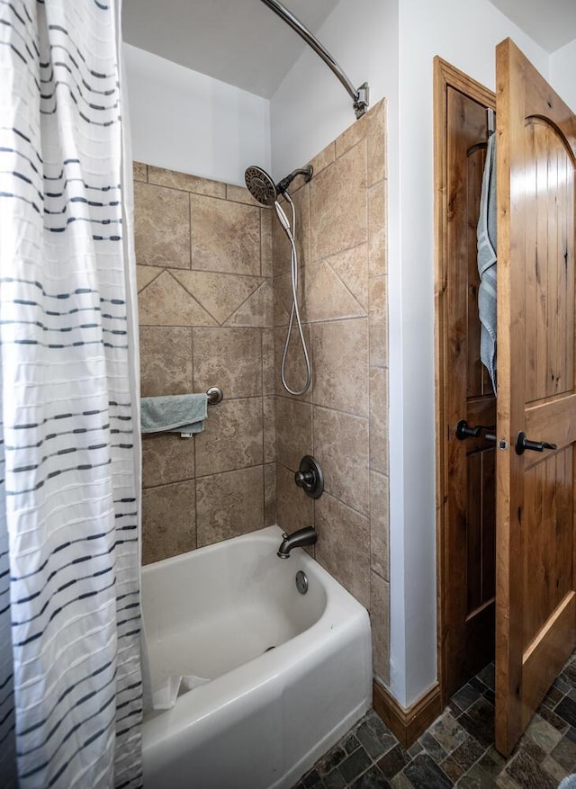 full bathroom featuring shower / tub combo with curtain and stone finish flooring