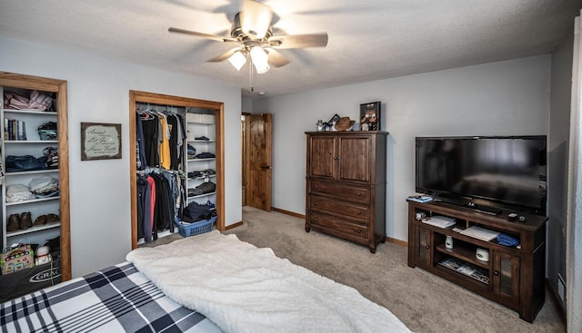 bedroom with a textured ceiling, baseboards, light colored carpet, a ceiling fan, and a closet