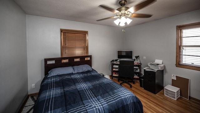 bedroom featuring ceiling fan, baseboards, and wood finished floors