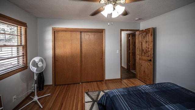bedroom with wood finished floors, a closet, a ceiling fan, and baseboards