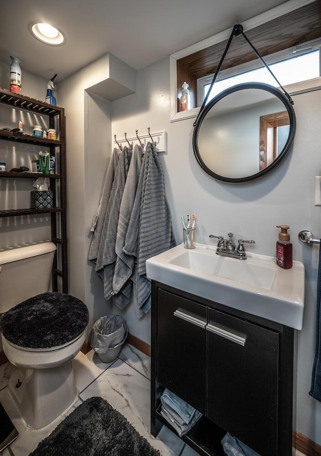 bathroom with marble finish floor, toilet, and vanity
