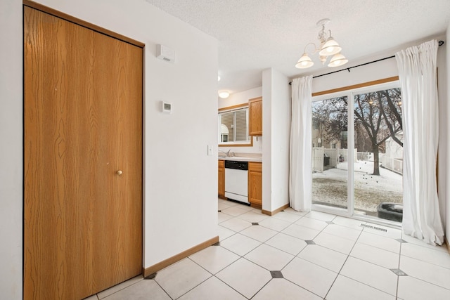 unfurnished dining area featuring a sink, a chandelier, a textured ceiling, baseboards, and visible vents