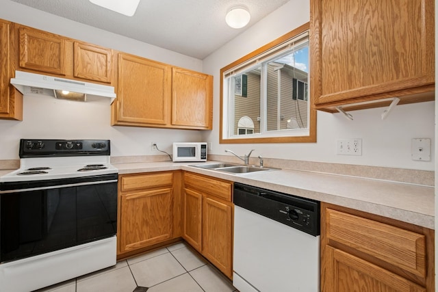 kitchen featuring white appliances, light countertops, under cabinet range hood, and a sink