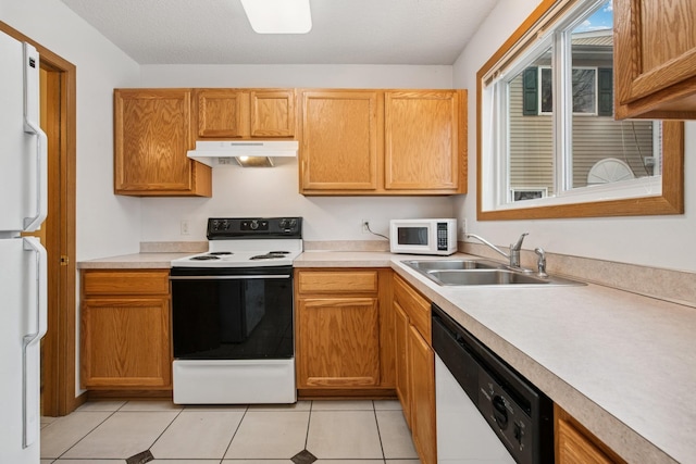 kitchen featuring light countertops, white appliances, light tile patterned floors, under cabinet range hood, and a sink