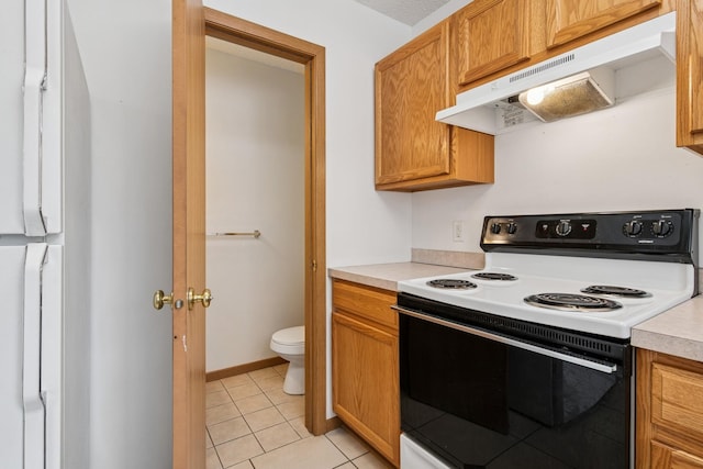 kitchen with electric range, light countertops, light tile patterned flooring, and under cabinet range hood
