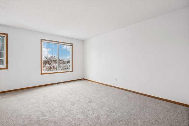 unfurnished room featuring baseboards, visible vents, carpet floors, and a textured ceiling