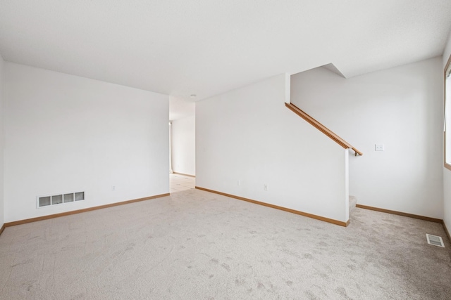 unfurnished living room featuring stairs, visible vents, baseboards, and carpet flooring