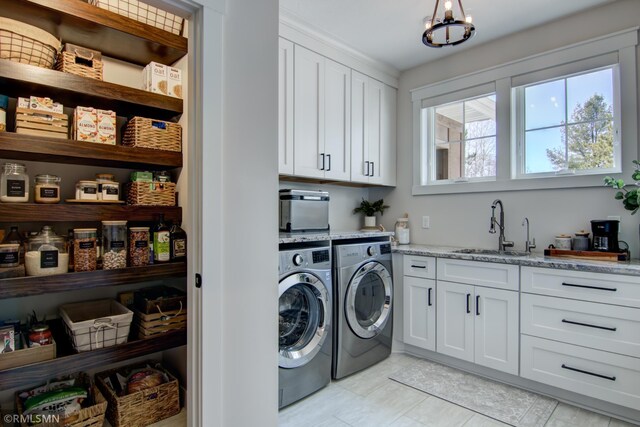 clothes washing area featuring light tile patterned floors, an inviting chandelier, a sink, cabinet space, and washer and clothes dryer