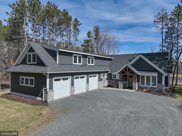 craftsman inspired home featuring a shingled roof, stone siding, and aphalt driveway