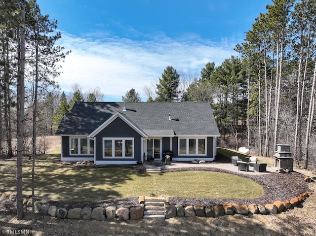 back of property with a patio area, a yard, and roof with shingles