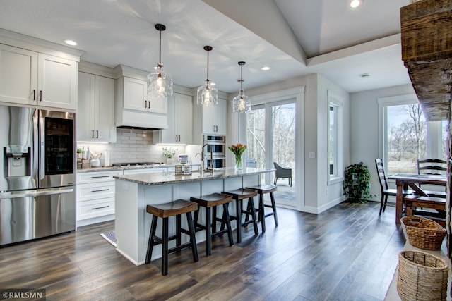 kitchen featuring baseboards, a kitchen breakfast bar, stainless steel appliances, backsplash, and light stone counters