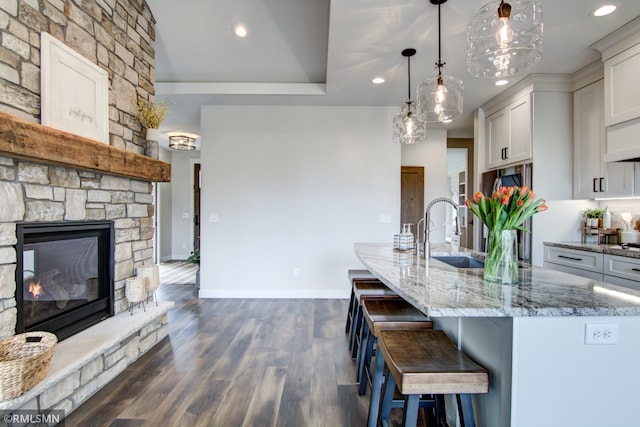 kitchen featuring a sink, light stone countertops, recessed lighting, and a fireplace