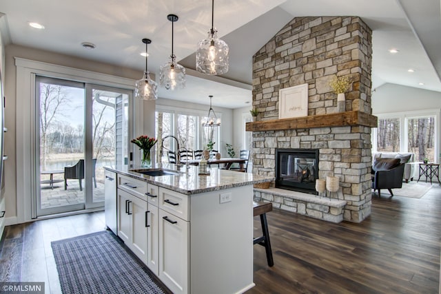 kitchen featuring white cabinets, vaulted ceiling, a breakfast bar, a sink, and open floor plan