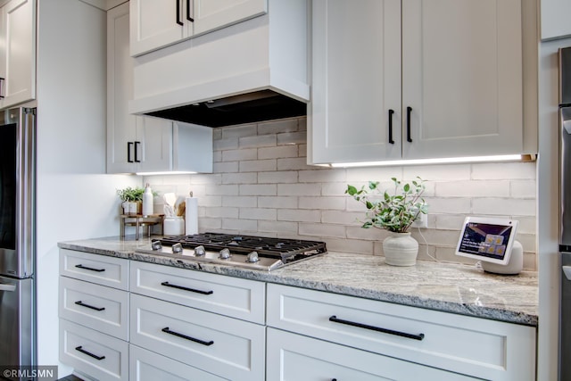 kitchen featuring custom range hood, decorative backsplash, white cabinetry, and stainless steel appliances