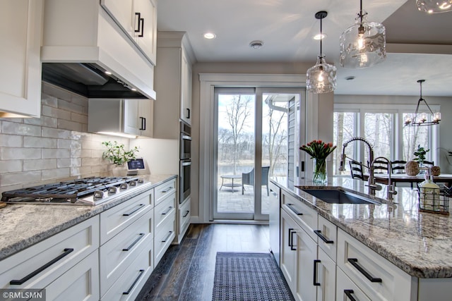 kitchen featuring premium range hood, white cabinets, dark wood-type flooring, stainless steel appliances, and a sink