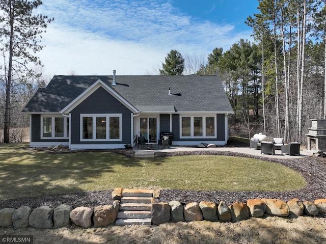 back of property with a patio, a shingled roof, and a lawn