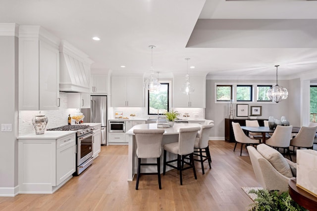 kitchen featuring white cabinetry, a breakfast bar area, light countertops, and premium appliances