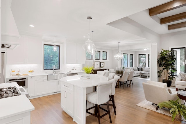 kitchen with decorative backsplash, light countertops, light wood-style flooring, open floor plan, and a kitchen breakfast bar