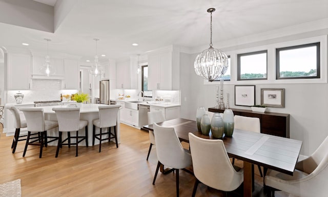 dining area with crown molding, light wood-type flooring, a notable chandelier, and recessed lighting