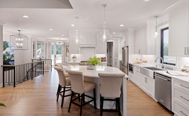 kitchen featuring white cabinetry, light countertops, a breakfast bar area, a sink, and appliances with stainless steel finishes
