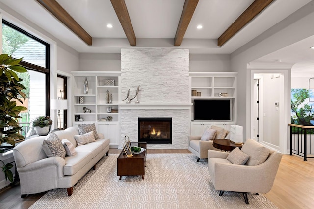 living room with a fireplace, light wood-style flooring, and beam ceiling