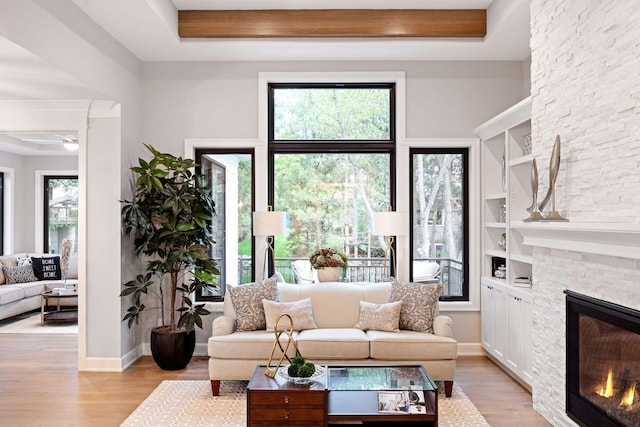 living room featuring baseboards, ceiling fan, built in features, a fireplace, and wood finished floors