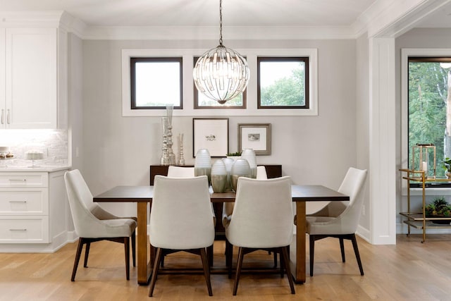 dining room featuring ornamental molding, a notable chandelier, baseboards, and light wood finished floors