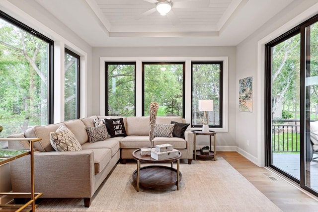sunroom featuring baseboards, visible vents, wood finished floors, and a raised ceiling