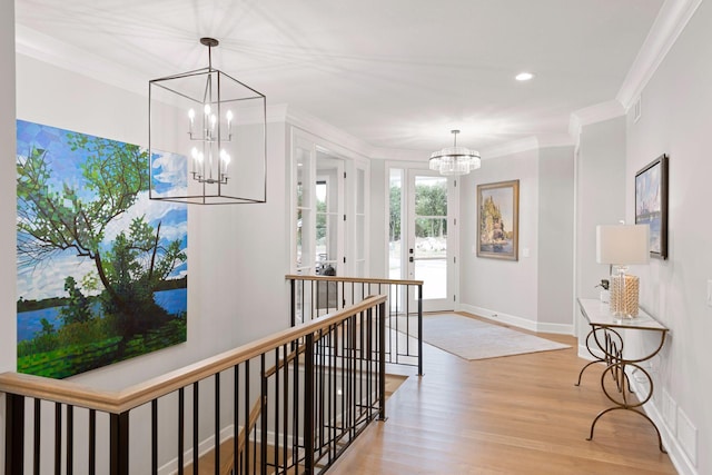 corridor featuring an upstairs landing, crown molding, baseboards, light wood-style flooring, and a notable chandelier