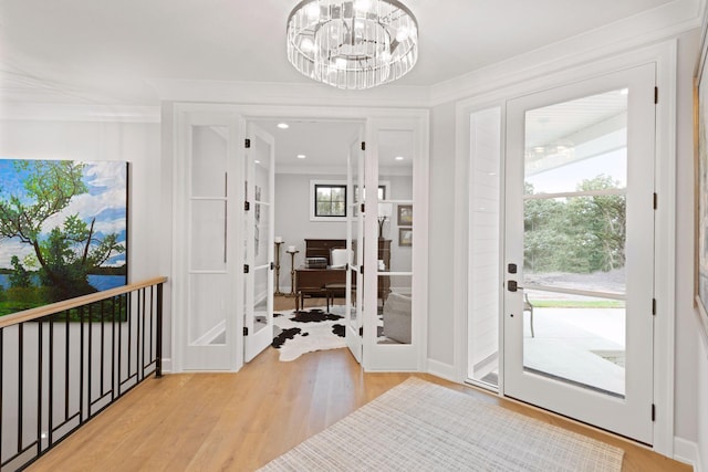 foyer with light wood finished floors, plenty of natural light, and ornamental molding