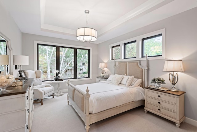 bedroom with light carpet, baseboards, an inviting chandelier, and a raised ceiling