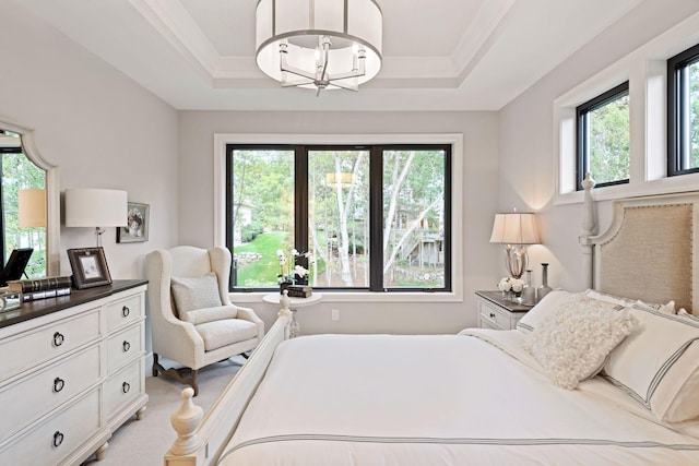 bedroom with a notable chandelier, a tray ceiling, and multiple windows