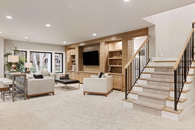 living room with recessed lighting, stairway, wooden walls, and light colored carpet
