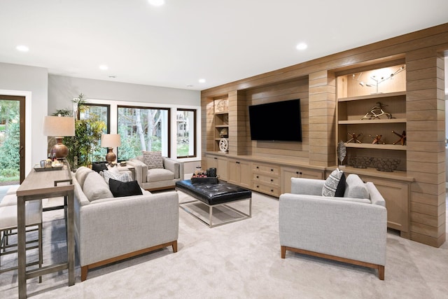 living area with light colored carpet, wooden walls, built in features, and recessed lighting