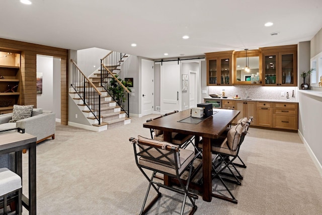 dining space featuring light colored carpet, a barn door, stairway, and recessed lighting