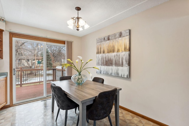 dining room with a chandelier and baseboards