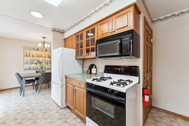 kitchen featuring a notable chandelier, gas range oven, black microwave, freestanding refrigerator, and light floors