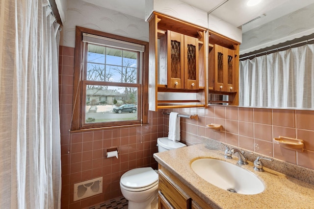 bathroom featuring vanity, visible vents, tile walls, and toilet